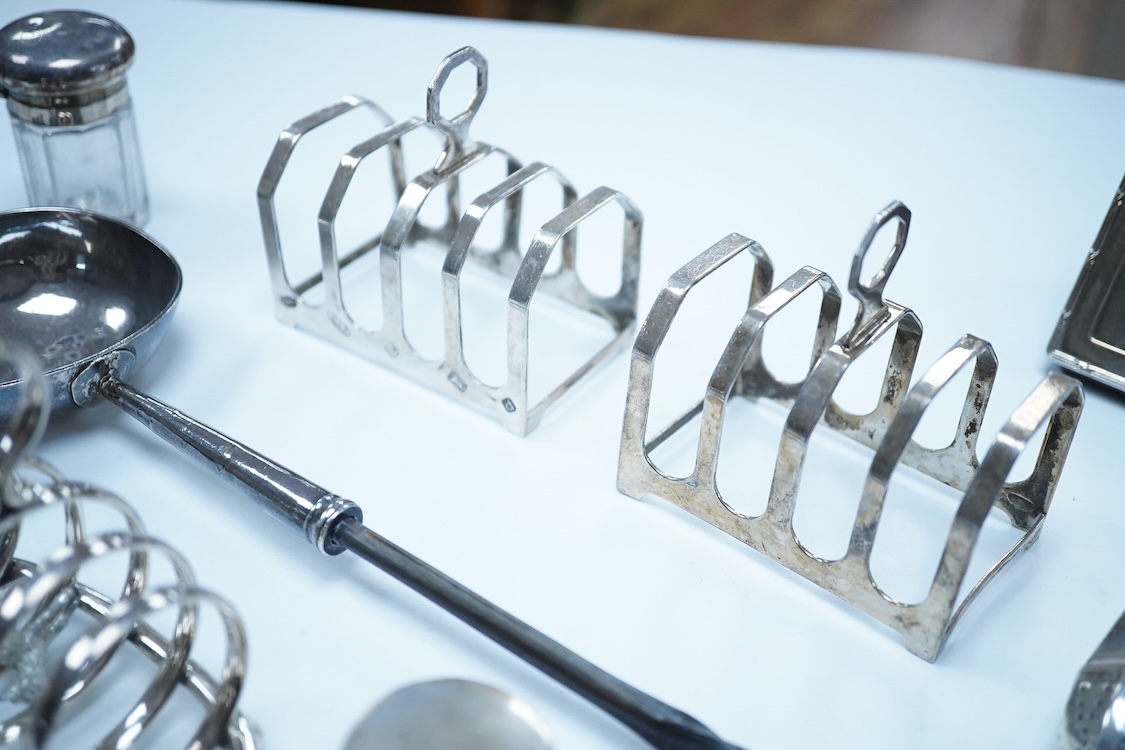A group of assorted silver, to include a pair of modern five bar toast racks, a George V card case, a sterling vesta case, four assorted condiments, two mounted toilet bottles, mounted timepiece, a modern wooden handled